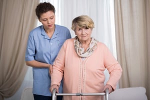 Aged disabled lady with walker and her helpful caregiver