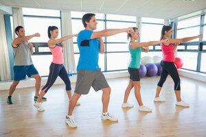 Full length of sporty people doing power fitness exercise at yoga class