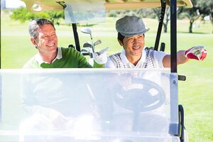 Golfing friends driving in their golf buggy at the golf course 