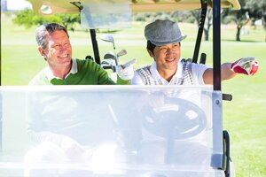 Golfing friends driving in their golf buggy at the golf course
