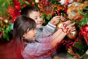 Happy kids decorating a Christmas tree with balls