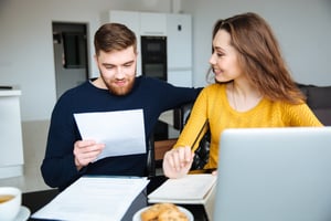 Happy couple calculating bills at home