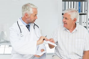 Male doctor giving a prescription to his senior patient at the medical office