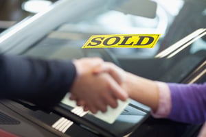 People shaking hands in front of a sold car-1