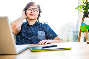 Smiling asian businessman listening to music in office