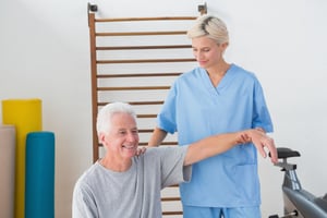 Senior man stretching with his therapist in fitness studio