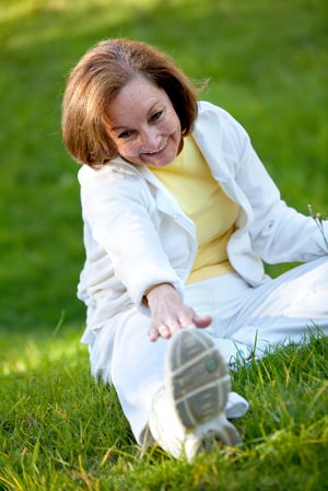 Senior woman stretching her legs at the park