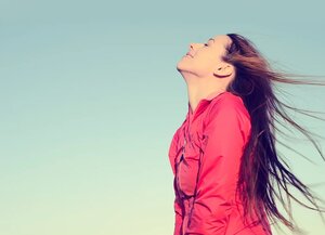 Woman smiling looking up to blue sky taking deep breath celebrating freedom