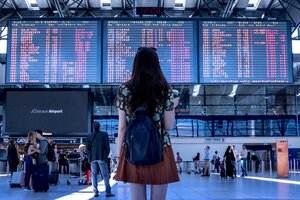 woman looking at airport arrival and departure times board