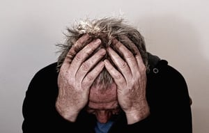 older man headache hands on head