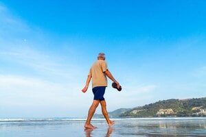 older man walking on beach