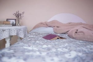 unmade purple bed with book on top