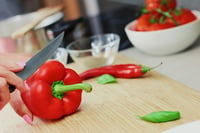 woman slicing red bell paper on cutting board