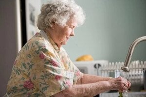 older woman preparing mean of fish in kitchen