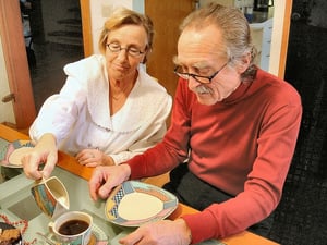 older couple at breakfast pouring cream into coffee