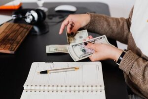 crop-businesswoman-counting-money-while-sitting-at-desk-4475525-1