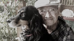 older man smiling holding therapy dog