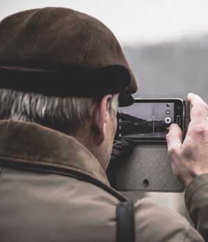 older man outside taking photo on mobile phone