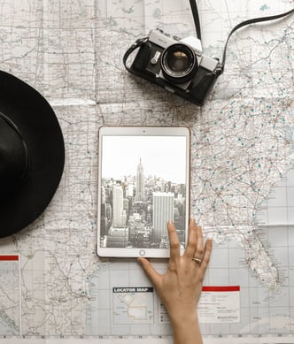 person touching silver ipad view of skyline over map with camera