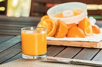 fresh squeezed orange juice with squeezed orange peels in background