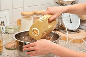 woman using hand mixer and lightweight metal mixing bowl in kitchen