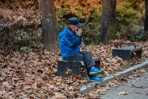 man playing harmonica on bench in park