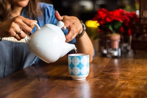 Older woman pouring pot of hot tea