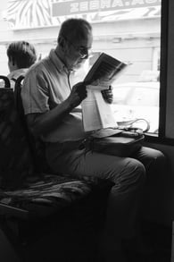 man reading newspaper on bus