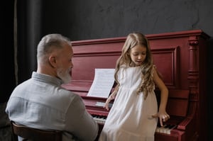 grandfather playing piano with granddaughter