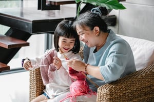 grandmother and granddaughter knitting together smiling
