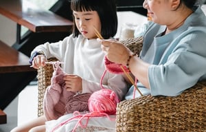 grandmother and granddaughter knitting together at home