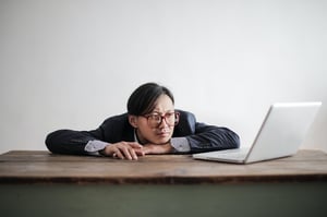 older man in suit bored and distracted at his laptop, unproductive