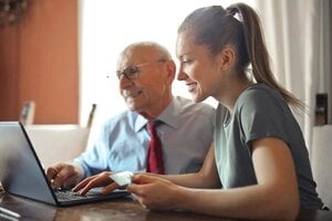 younger granddaughter helping grandfather with financial work
