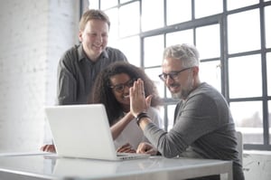 man with gray hair high fiving younger coworker at work