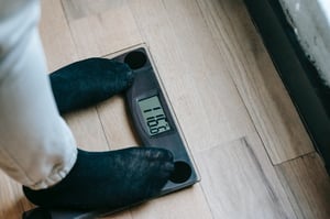 older person with compression socks standing on scale