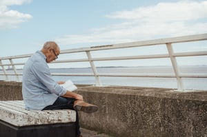 older man alone reading on a pier
