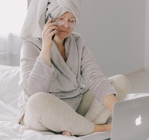 older woman moisturizing after shower on bed