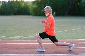 older man performing calishtenic exercise on a track outdoors