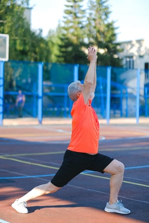 Older man stretching outdoors on a track