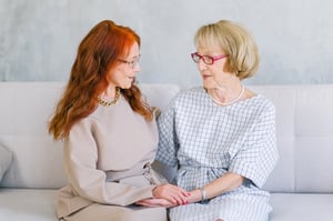 two women sitting together talking on a couch