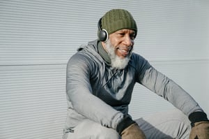 older man listening to music in headphones outside 