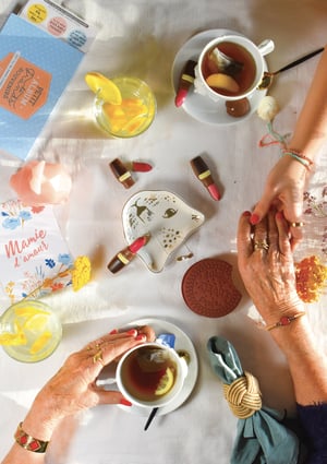 older couple holding hands over the table with a cup of tea