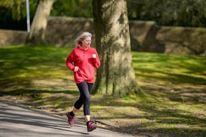 older woman in red sweatshirt jogging in the park 
