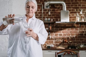 older woman pouring a glass of water in kitchen