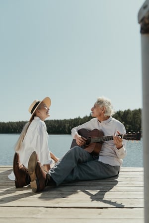older couple playing music together on dock over lake outside