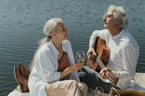 older couple sitting on dock playing music and singing