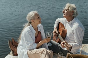 older couple sitting on dock playing music and singing