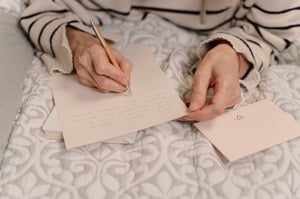 older woman writing a letter in bed