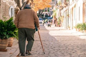older man walking in the street with a walking cane