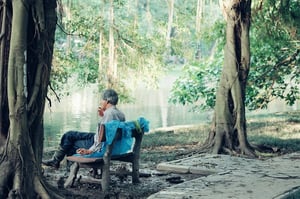 older man smoking outside on a bench